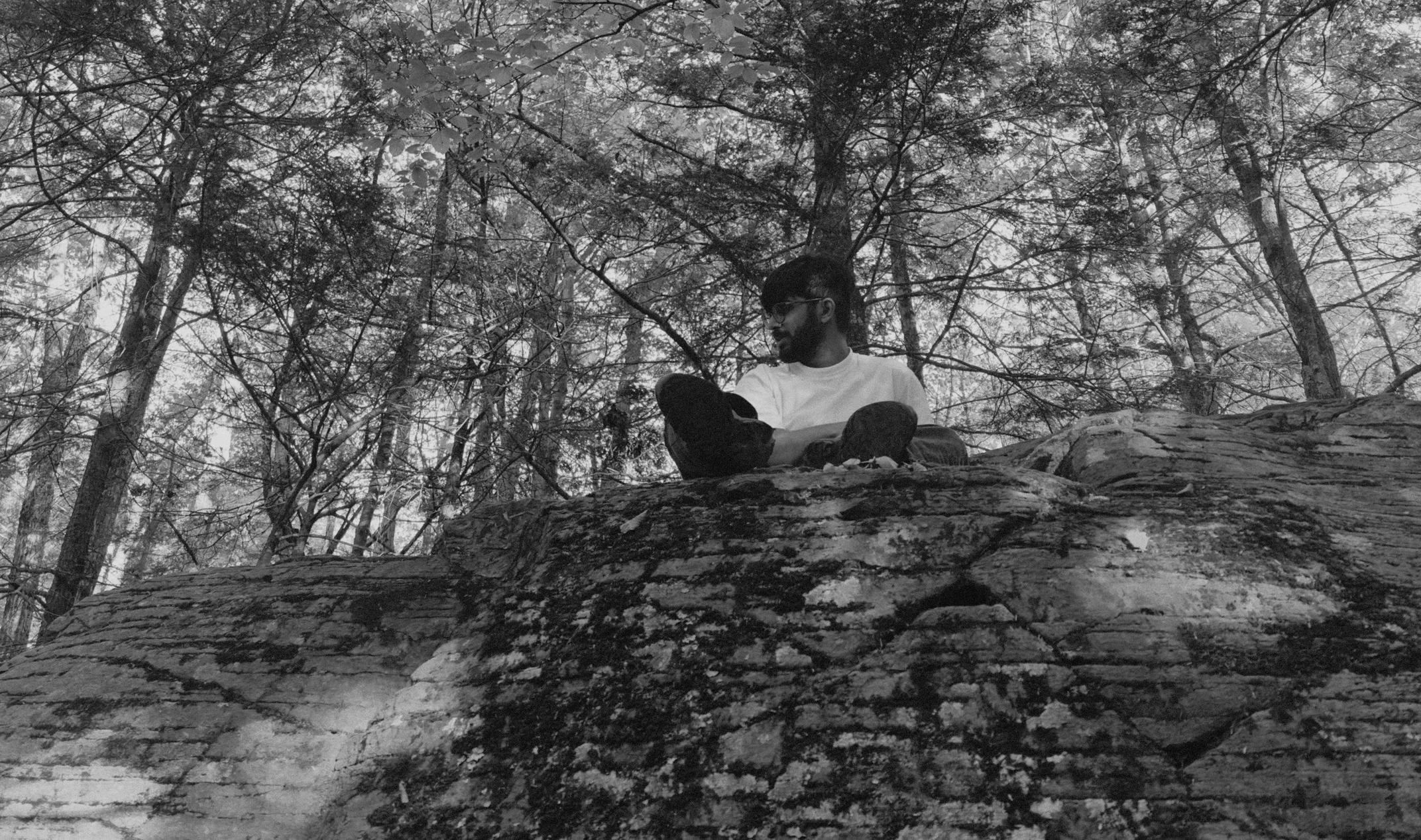 Usmaan sitting on a rock in a forest